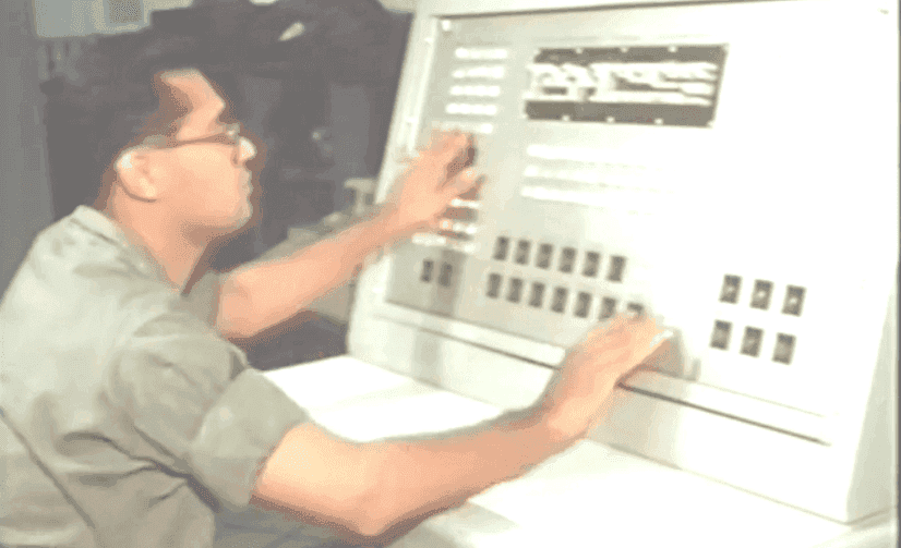 A military officer working in front of a 60s-era messaging terminal with large knobs and buttons.