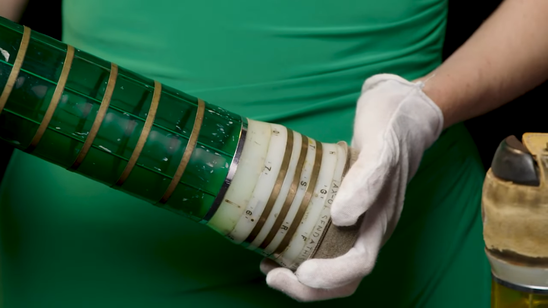 A closeup photograph of a CIA pneumatic tube canister, depicting the rotating brass rings for indicating the container’s intended destination